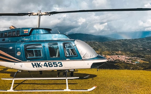 helicopter on a hill with small town colombia at the bottom helicopter tours from medellin