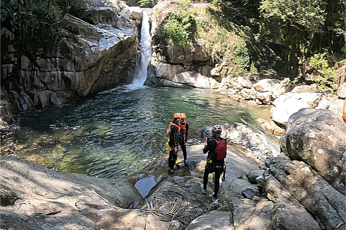 Three people standing by a green pool while canyoning medellin